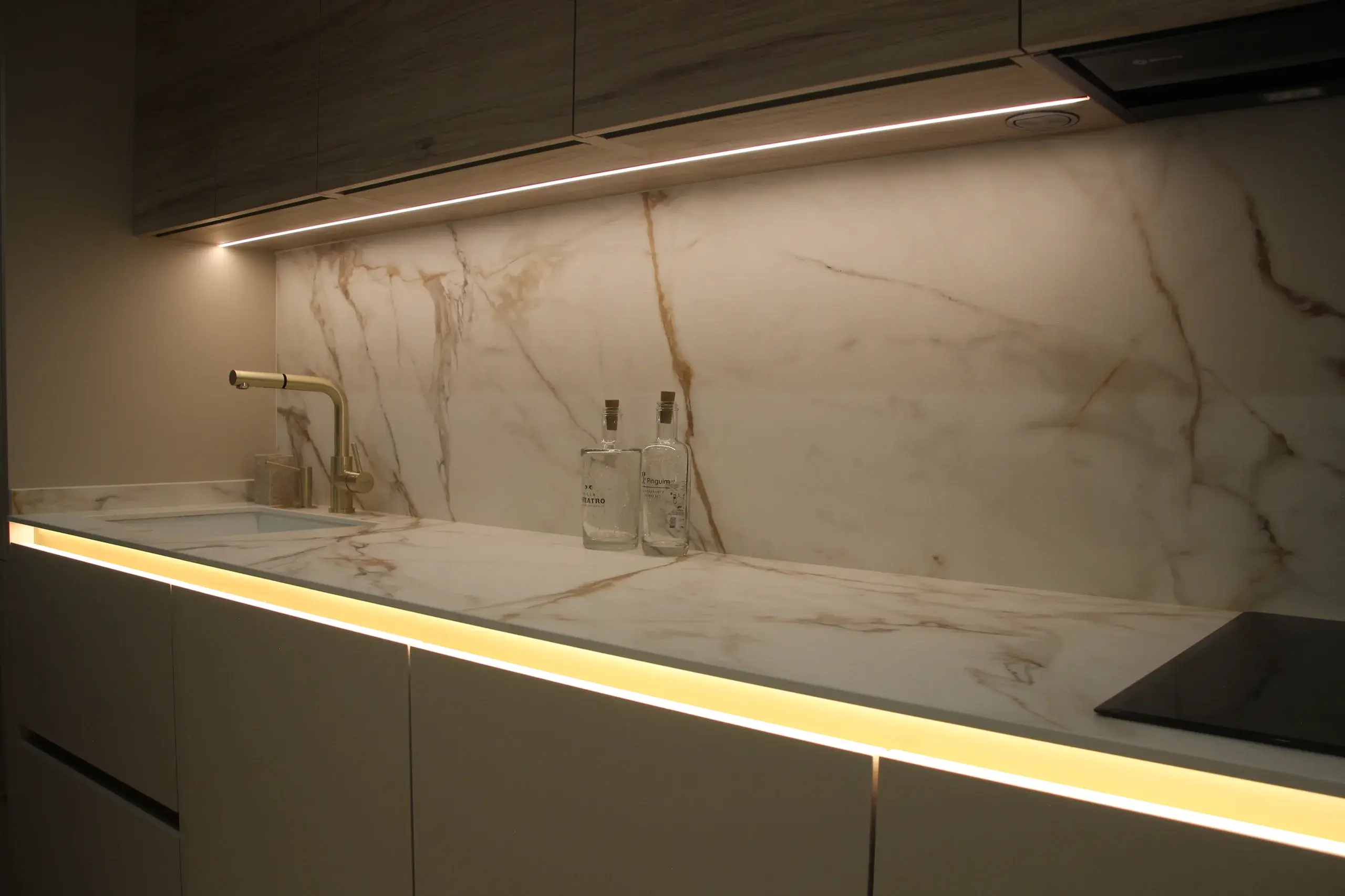 Cocina en cachemir con gola iluminada, altos de roble y encimera Calacatta Gold con luz LED