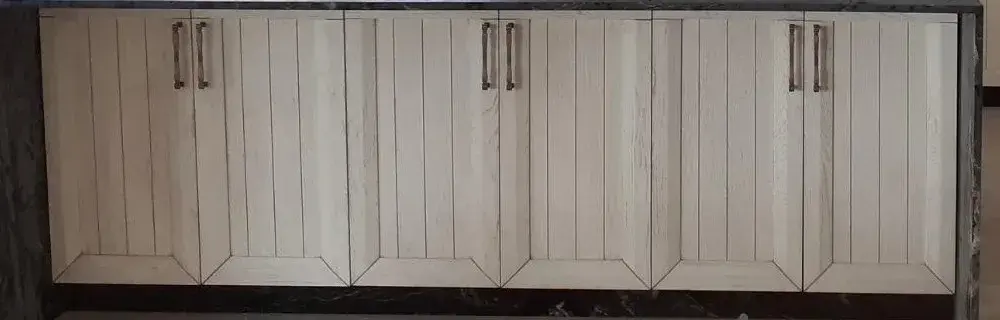 Detalle de frente de madera clara con tiradores metálicos