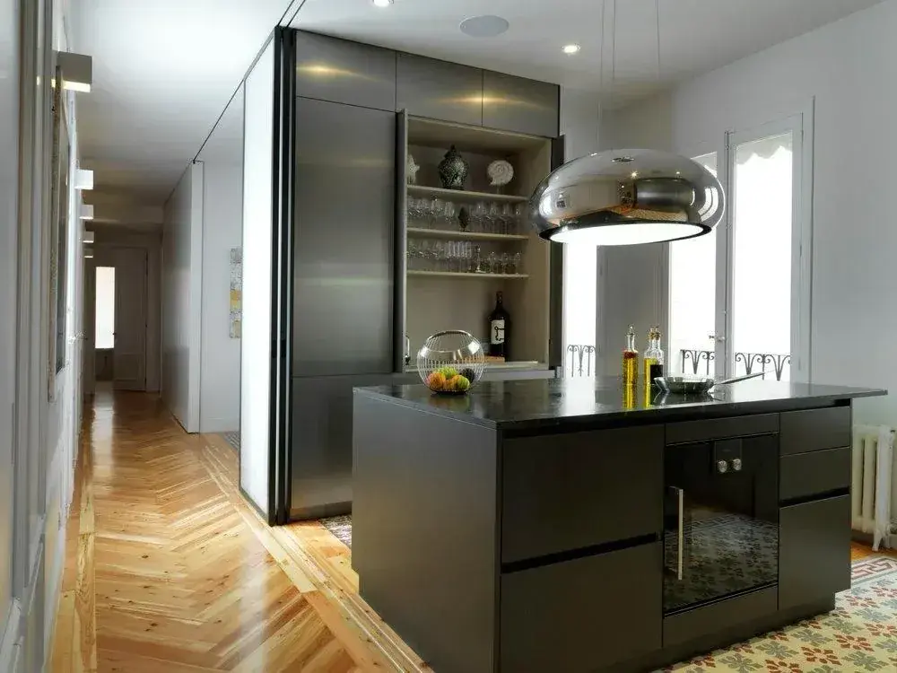 Cocina en verde oscuro con isla, vitrina de aluminio y suelo de espiga