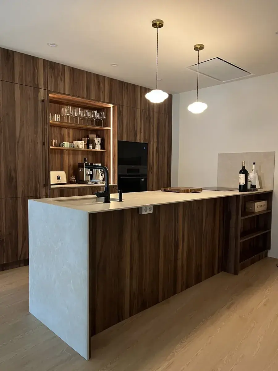 Cocina en nogal con isla de piedra clara y estantería abierta