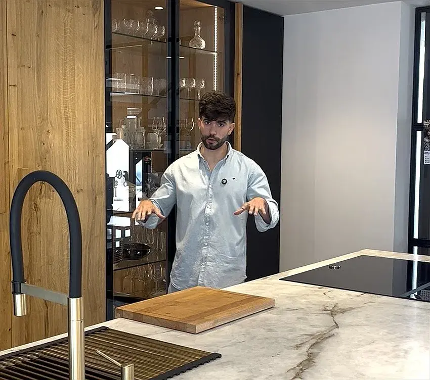Jorge González Ruiz en una cocina con frentes de roble, vitrina iluminada e isla de piedra natural