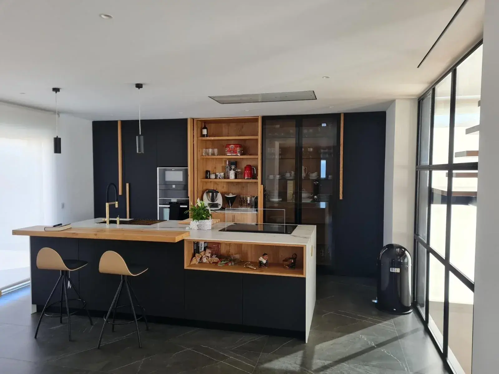 La cocina terminada, en negro mate con isla y barra de roble
